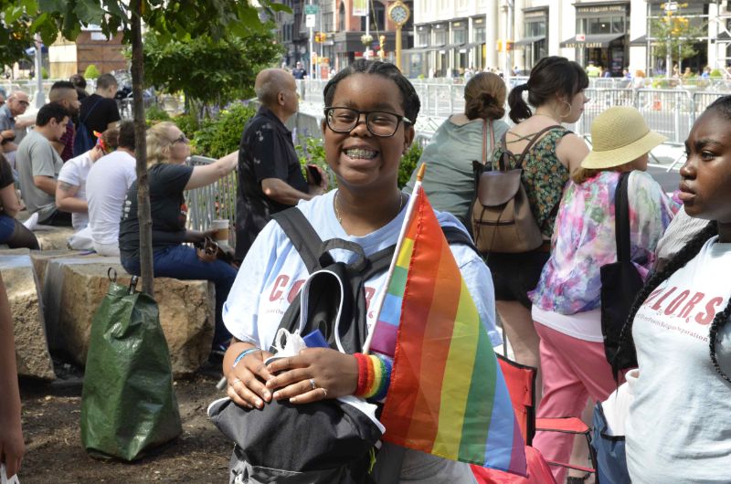 Girl holding a rainbow flag smiling.